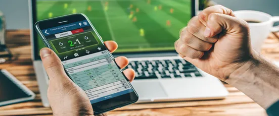Un utilisateur parie en ligne sur son téléphone tout en regardant un match en streaming via Golden Palace Sport sur ordinateur