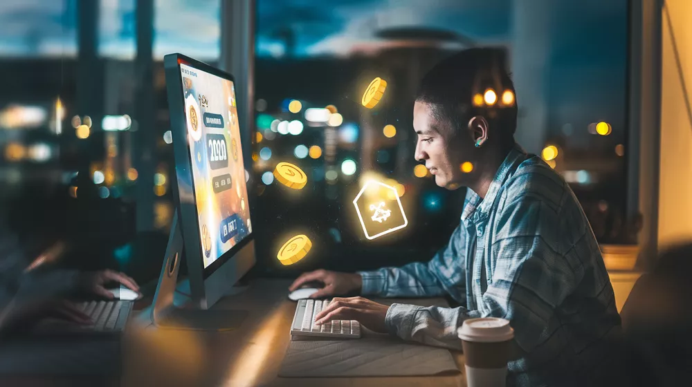 Jeune homme jouant à un jeu en ligne pour gagner de l’argent, écran lumineux affichant des récompenses virtuelles