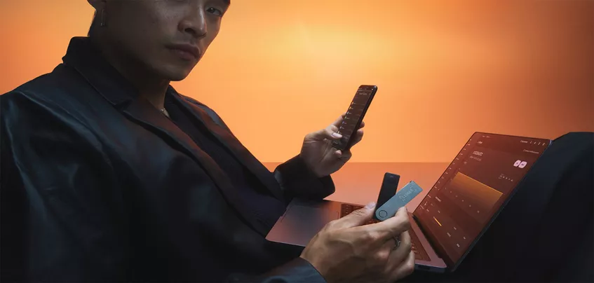Utilisateur gérant ses cryptomonnaies avec un portefeuille Ledger, un smartphone et un ordinateur portable